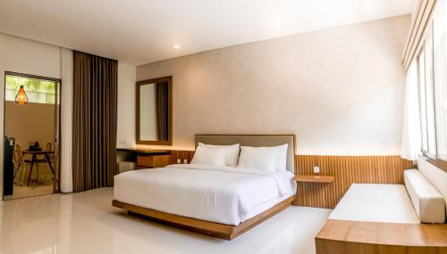 um quarto com uma grande cama branca e uma secretária em D'Green Kuta Managed by ARM Hospitality em Legian
