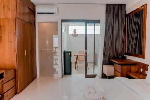 a bedroom with a bed and a desk and a table at D'Green Kuta Managed by ARM Hospitality in Legian