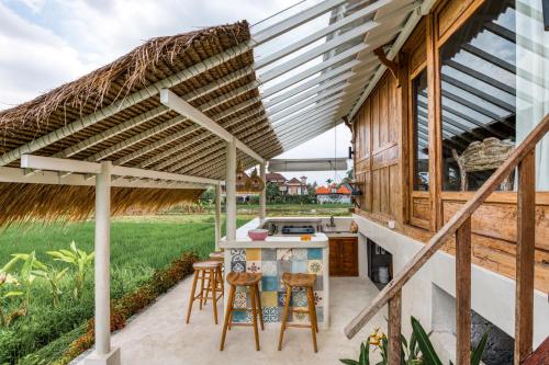 an outdoor kitchen with a pergola and stools at The Rice Joglo Eco-Stay in Ubud