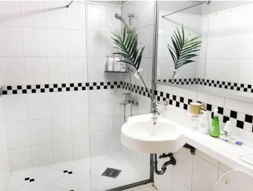 La salle de bains blanche est pourvue d'un lavabo et d'une douche. dans l'établissement Private house near Hongdae with Elevator, à Séoul