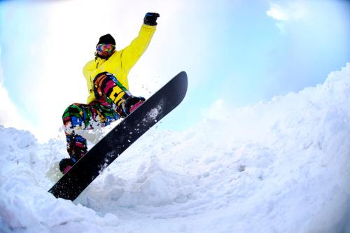 a man flying through the air while riding a snowboard at Brick House Furano in Furano