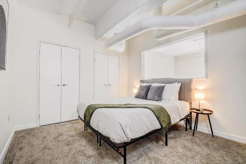 a white bedroom with a bed and a window at CozySuites - 2BR with Direct Skybridge Access #9 in Indianapolis