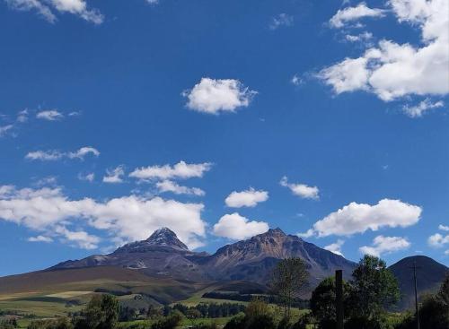 a view of a mountain with a blue sky and clouds at Casa Andina Los Ilinizas in Chaupi