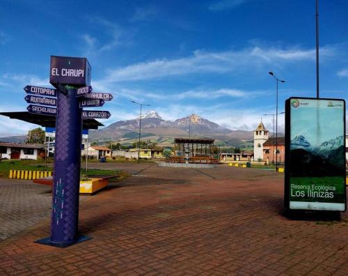 un panneau de rue dans une ville avec des montagnes en arrière-plan dans l'établissement Casa Andina Los Ilinizas, à Chaupi