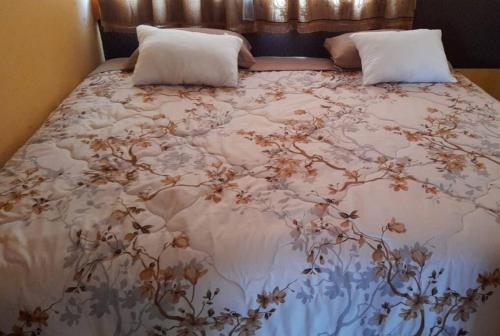 a bed with a floral bedspread and pillows on it at Casa Andina Los Ilinizas in Chaupi