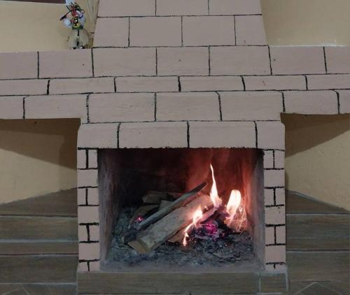 a brick fireplace with a fire in it at Casa Andina Los Ilinizas in Chaupi