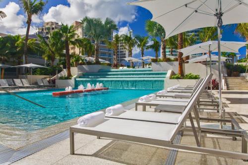 a pool with chairs and umbrellas next to a resort at La Concha Renaissance San Juan Resort in San Juan