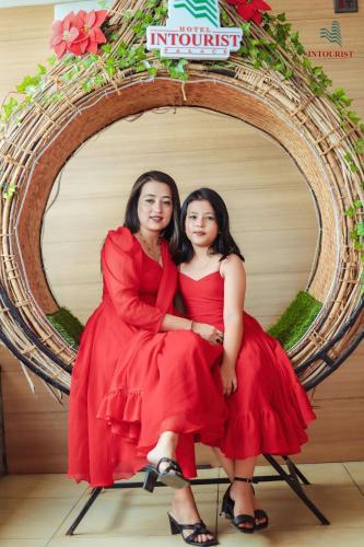 two women in red dresses sitting in a circle at Hotel Intourist Palace in Itahari
