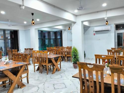 an empty restaurant with wooden tables and chairs at Hotel Saan in Baharampur