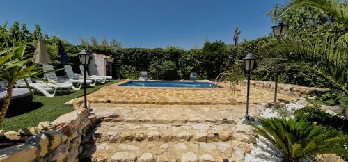 a backyard with a swimming pool and a stone wall at Cortijo Rodeo. Alojamiento Rural in Carcabuey