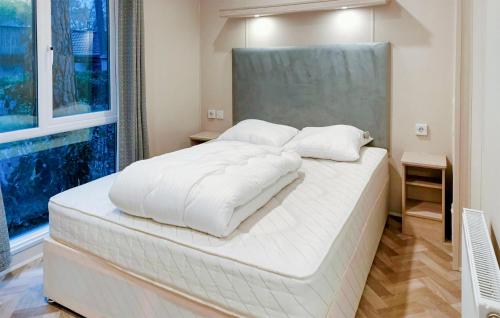 een groot wit bed in een kamer met een raam bij 2 Bedroom Nice stacaravan In Harderwijk in Harderwijk