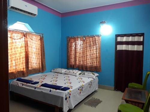 a bedroom with a bed with blue walls and curtains at HOTEL NAKSHATRA in Digha