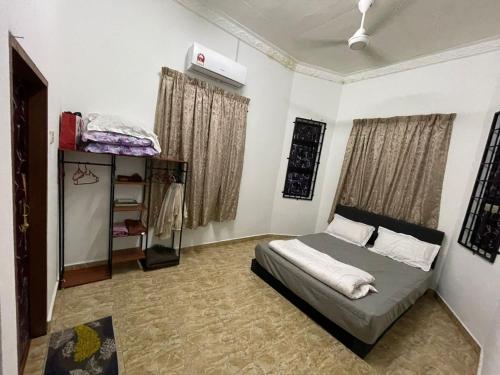 een slaapkamer met een bed, een plank en ramen bij Teratak Zaa D’Homestay in Kota Bharu