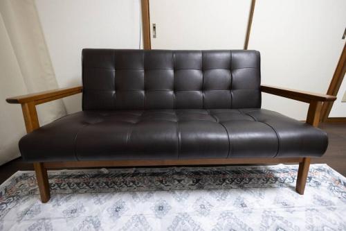 a black leather couch sitting on top of a rug at 所沢レイクサイドハウス in Higashiyamato
