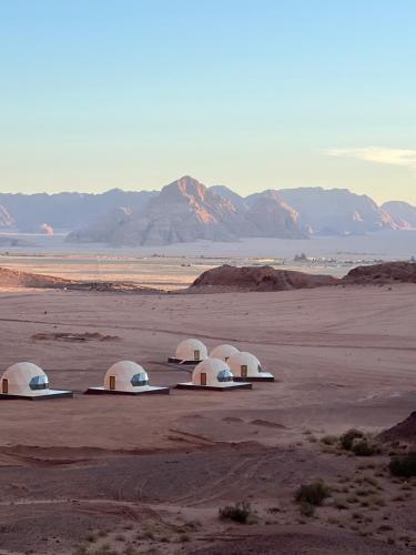 Queen's Magic Camp في Disah: أربعة قباب في صحراء مع جبال في الخلفية