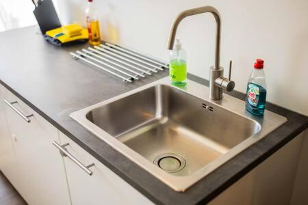 a kitchen counter with a sink and soda bottles at Stylish 50m² Two-Bedroom Apartment (SD-23-K) in Eindhoven