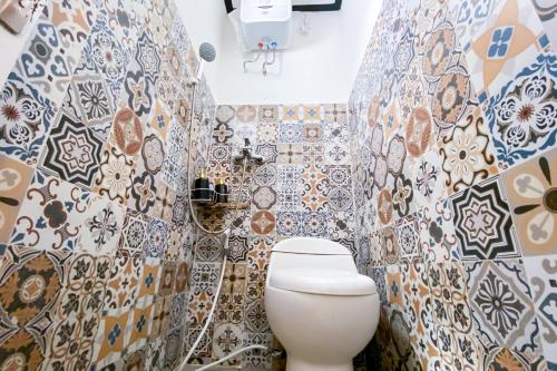 a bathroom with a toilet and tiles on the wall at Kana Guest House Mitra RedDoorz in Uluwatu