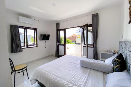 a white bedroom with a bed and a window at Kana Guest House Mitra RedDoorz in Uluwatu