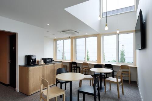 a waiting room with tables and chairs and windows at Kamishihoro Hotel in Kami-shihoro