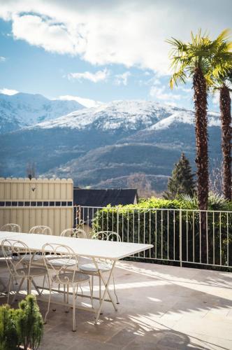 a table and chairs on a patio with snow covered mountains at Maison La Grande Ourse in Beaucens