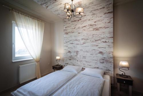 a bedroom with a bed and a brick wall at Aranyszarvas Panzió****, Étterem és Grillterasz in Szarvas