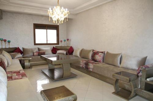 a living room with a large couch and a chandelier at Mahaj in Rabat