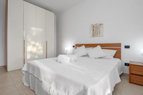 una camera da letto bianca con un grande letto con lenzuola bianche di Villa Marconi Apartment 5 a Golfo Aranci