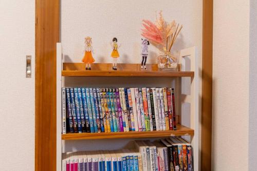 un estante de libros lleno de DVD y estatuillas en 301号室貸切！2DK/京成佐倉駅徒歩3分・電車成田空港20分・京成上野直結！厨房/風呂/畳/4名, en Sakura