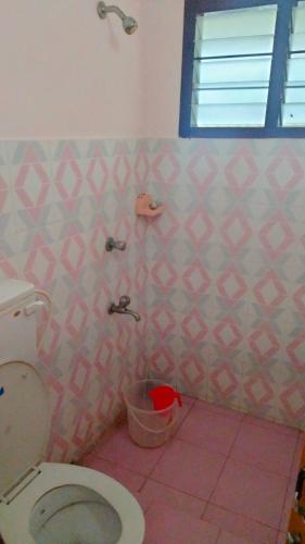bagno con servizi igienici e parete piastrellata rosa di Shakthi Residency a Alleppey