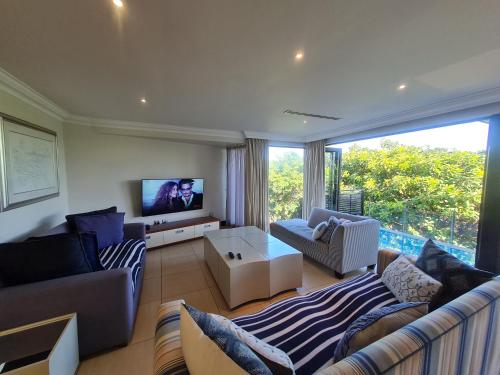 a living room with a couch and a tv at Zimbali - Luxury 4 Bedroom KRH1 in Ballito