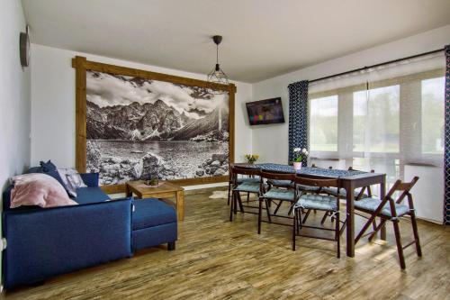 uma sala de estar com uma mesa de jantar e um sofá azul em Domki Magia Gór-nocleg obok Term em Szaflary