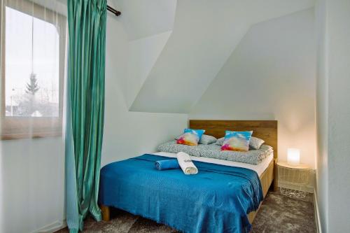 um quarto com uma cama com lençóis azuis e uma janela em Domki Magia Gór-nocleg obok Term em Szaflary