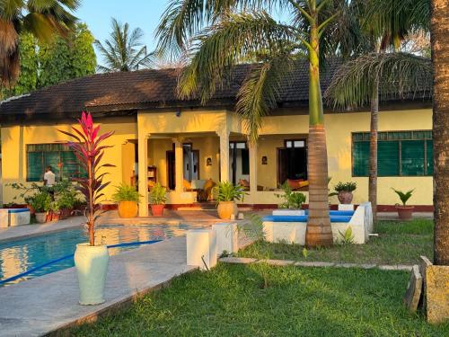 a house with a swimming pool and palm trees at Sawa Sawa Beach House in Msambweni