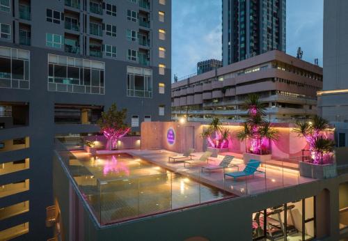 a rooftop patio with chairs and lights on a building at The Quarter Ratchathewi by UHG in Bangkok
