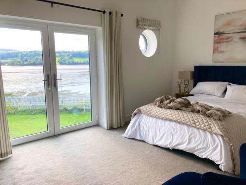 um quarto com uma cama e uma grande porta de vidro deslizante em Estuary View - Newly Built 3-Bed House em Conwy