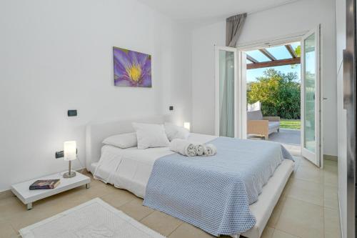 a white bedroom with a large bed and a sliding glass door at Villa Marconi Apartment 6 in Golfo Aranci