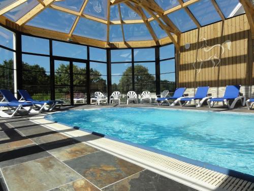 una piscina con sillas azules y un gran edificio de cristal en Mobil Home XXL 4 chambres - Camping Les Jardins du Morbihan, en Monterblanc