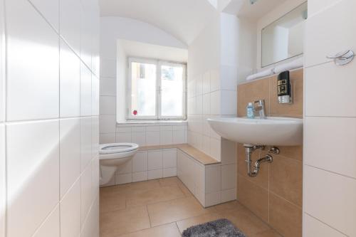a white bathroom with a toilet and a sink at Gasthaus Hinterbrühl in Salzburg