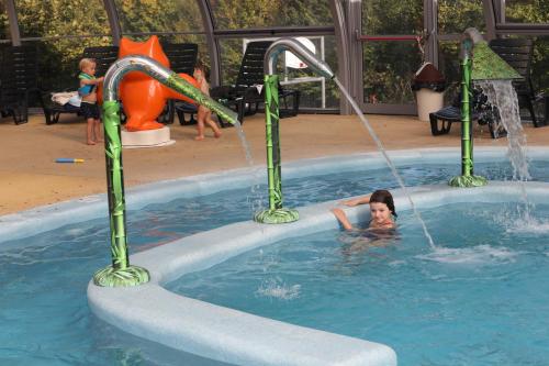 Une fille joue dans une piscine d'eau dans l'établissement Mobil Home XXL 4 chambres - Camping Le Clos Cacheleux, à Miannay