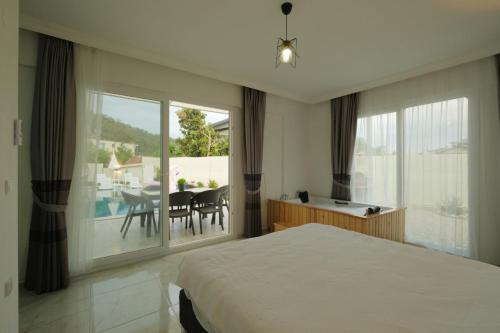 a bedroom with a bed and a balcony with a table at Villa Mila Fethiye in Fethiye