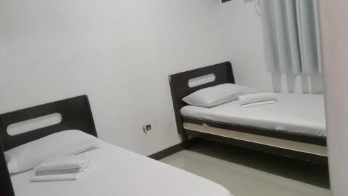 two beds in a small room with white walls at Sharana Pensionne in Davao City