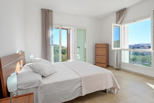 a white bedroom with a large bed and windows at Villa Marconi Apartment 7 in Golfo Aranci