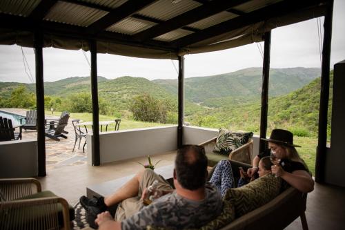 a group of people sitting on a couch looking at the mountains at Matatane Camp - Babanango Game Reserve in Nkwalini