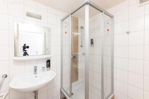a white bathroom with a shower and a sink at Gasthaus Hinterbrühl in Salzburg