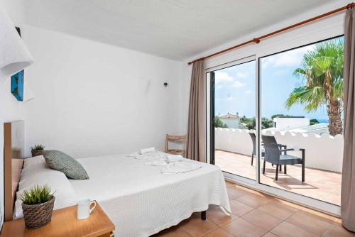 a bedroom with a white bed and a balcony at Bini Rosa in Binibeca