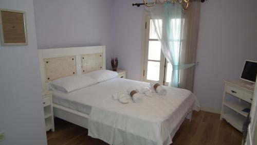 a bedroom with a bed with white sheets and a window at Gizemli Konak in Ayvalık