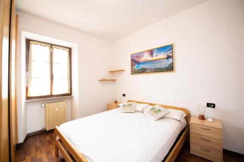 ein Schlafzimmer mit einem weißen Bett und einem Fenster in der Unterkunft Casa Marisa sul Garda in Toscolano-Maderno