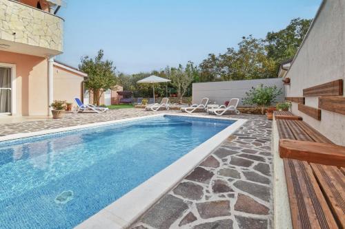 a swimming pool with chairs and a house at Holiday House Amna in Kaldanija