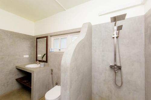 a bathroom with a shower and a toilet and a sink at Shangrela Beach Resort by ARK in Ambalangoda