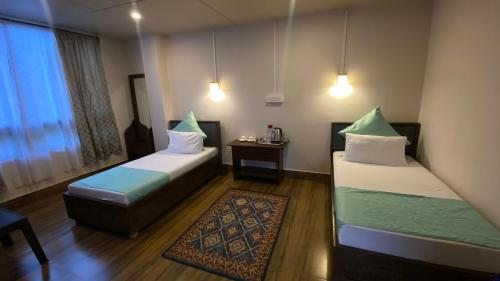 ein Hotelzimmer mit 2 Betten und einem Tisch in der Unterkunft HopInn in Mangan